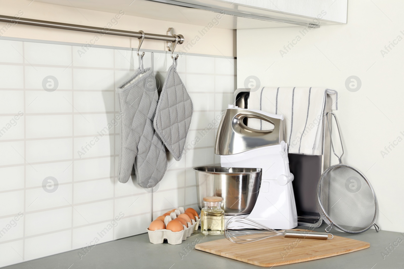 Photo of Set of clean cookware, utensils and eggs on table in modern kitchen