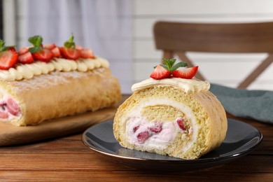 Delicious cake roll with strawberries and cream on gray plate, closeup