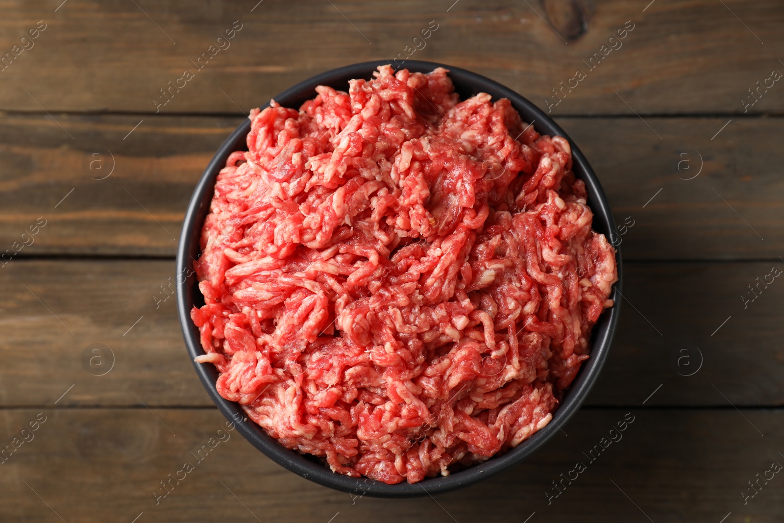 Photo of Raw ground meat in bowl on wooden table, top view