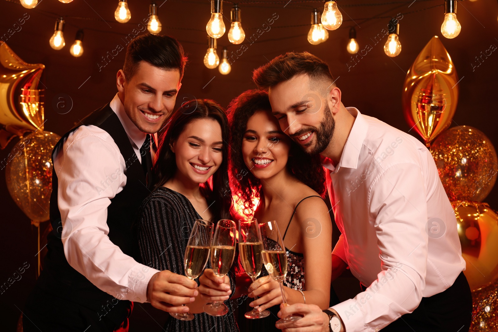 Photo of Happy friends with glasses of sparkling wine celebrating New Year indoors