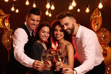 Happy friends with glasses of sparkling wine celebrating New Year indoors