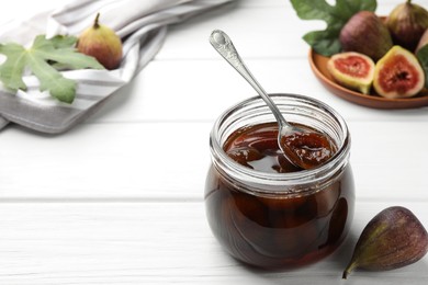 Jar of tasty sweet jam and fresh figs on white wooden table. Space for text