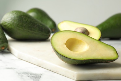 Delicious ripe avocados on table against light background