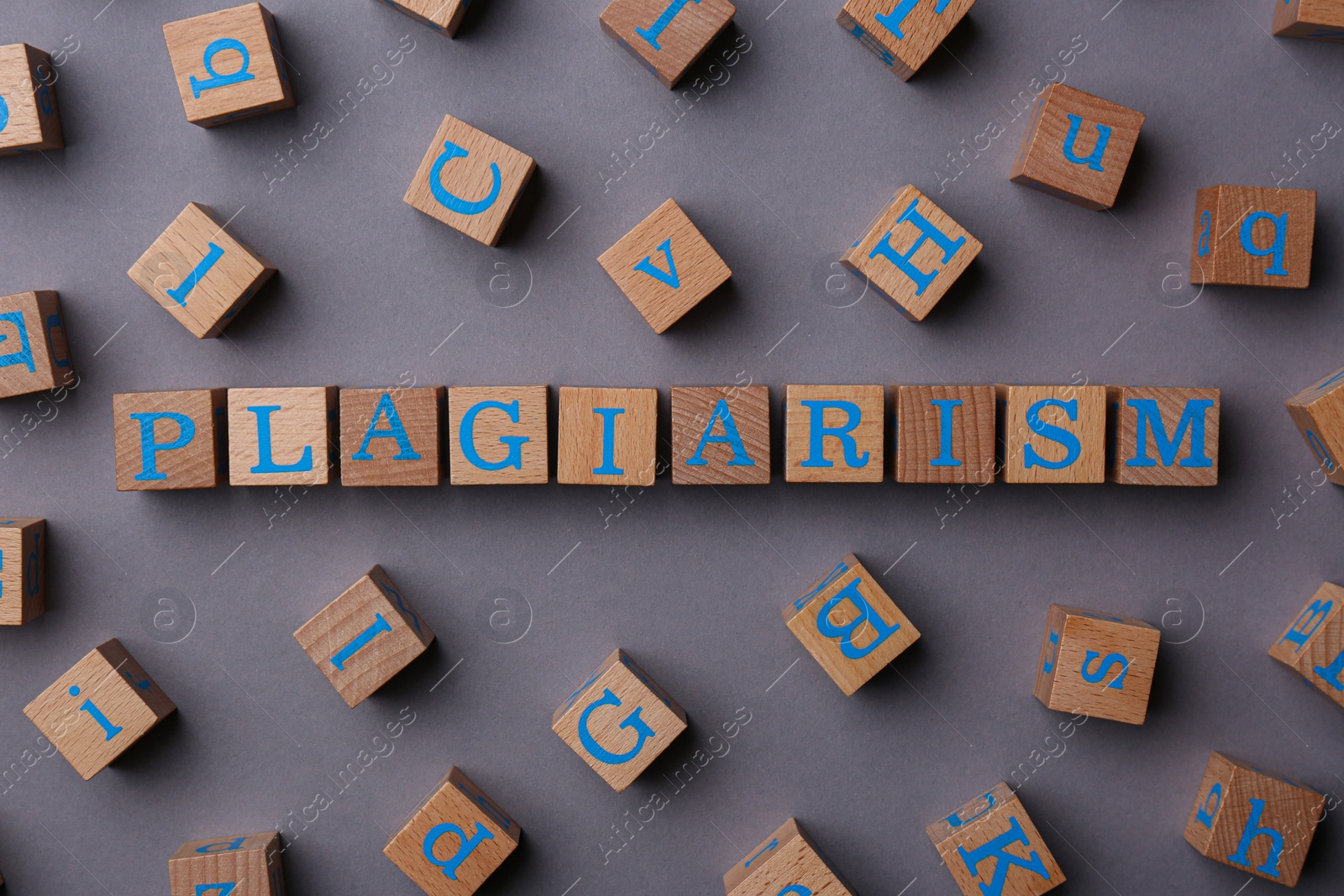 Photo of Wooden cubes with word Plagiarism on grey background, flat lay