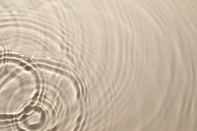 Photo of Rippled surface of clear water on beige background, top view