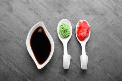 Photo of Swirl of wasabi paste, pickled ginger and soy sauce on grey table, flat lay