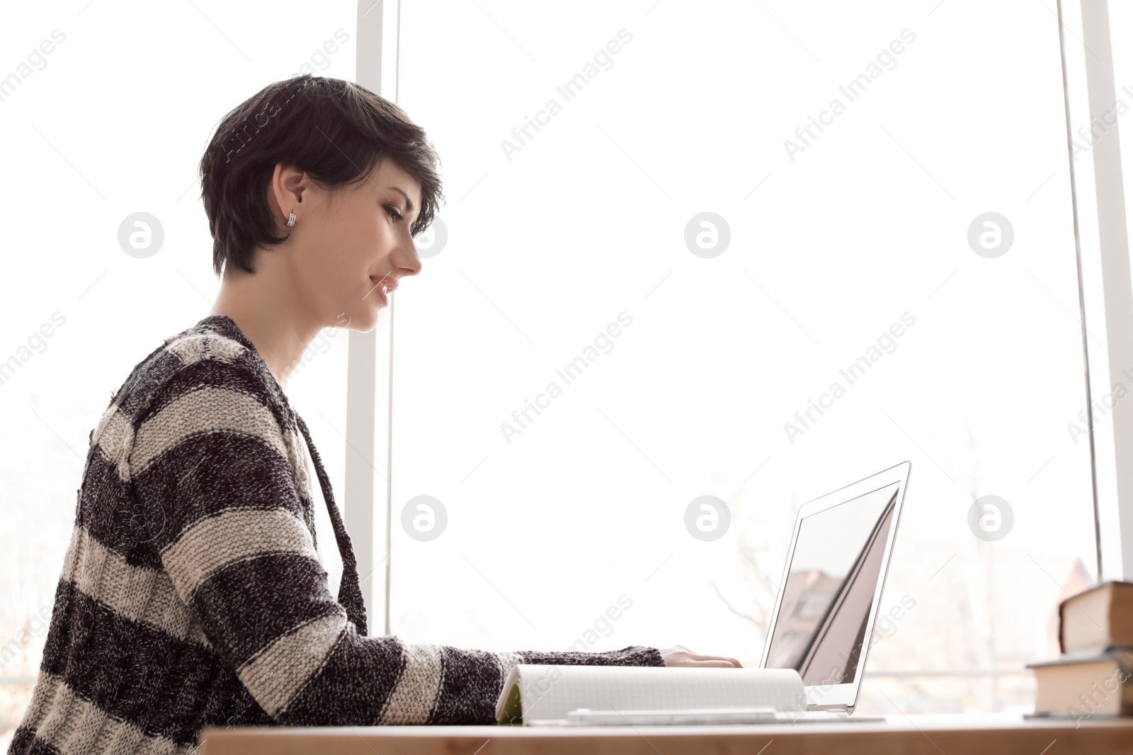 Photo of Young woman working with laptop at desk. Home office