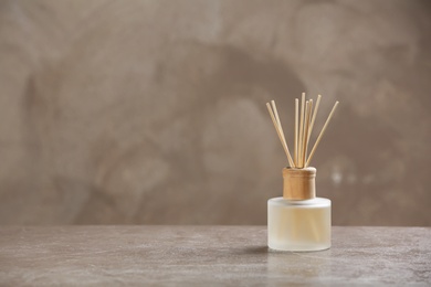 Photo of Aromatic reed freshener on table against grey background