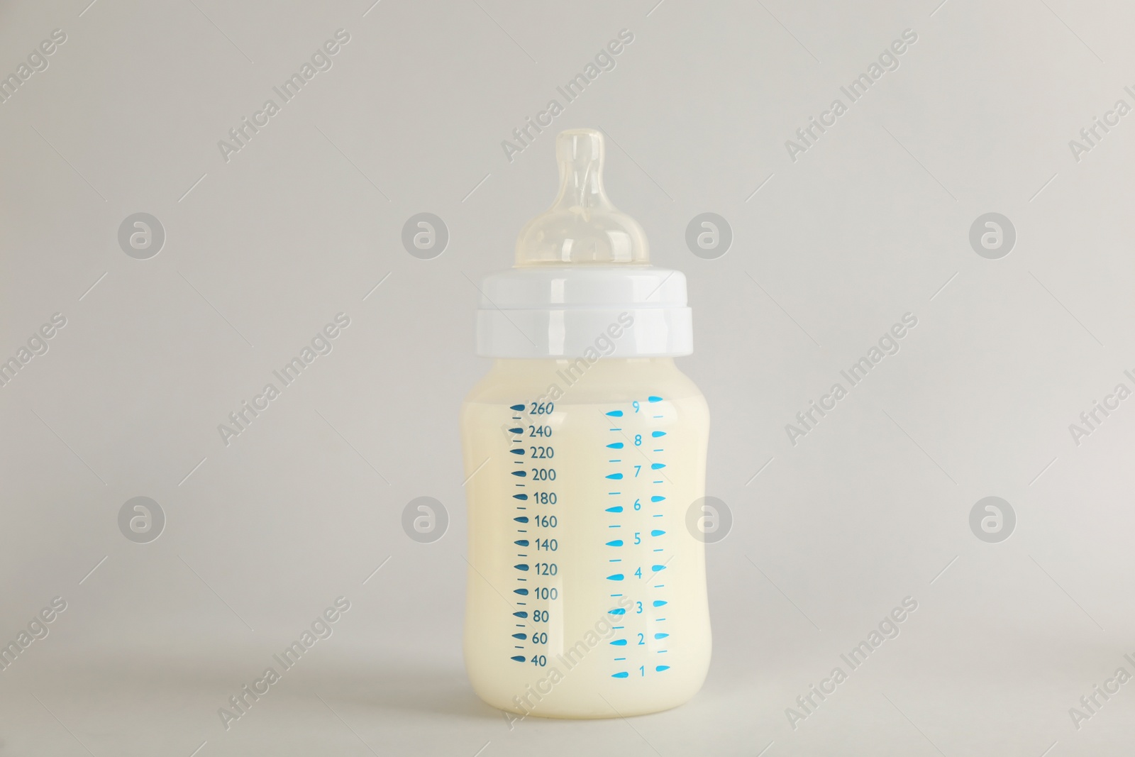 Photo of Feeding bottle with infant formula on light grey background. Baby milk