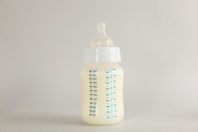 Photo of Feeding bottle with infant formula on light grey background. Baby milk