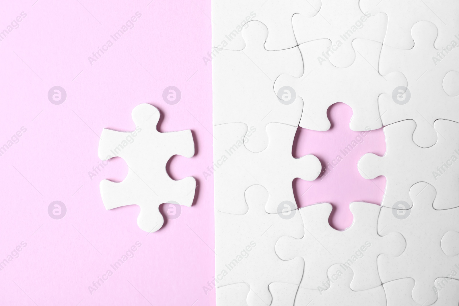 Photo of White puzzle with separated piece on pink background, flat lay