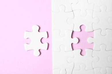 Photo of White puzzle with separated piece on pink background, flat lay