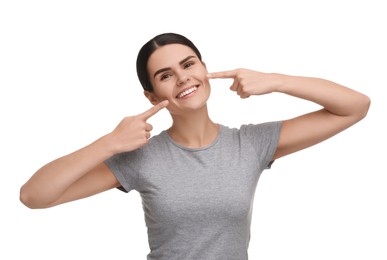 Photo of Young woman pointing at her clean teeth and smiling on white background