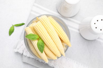 Canned baby corns with basil on light grey table, flat lay