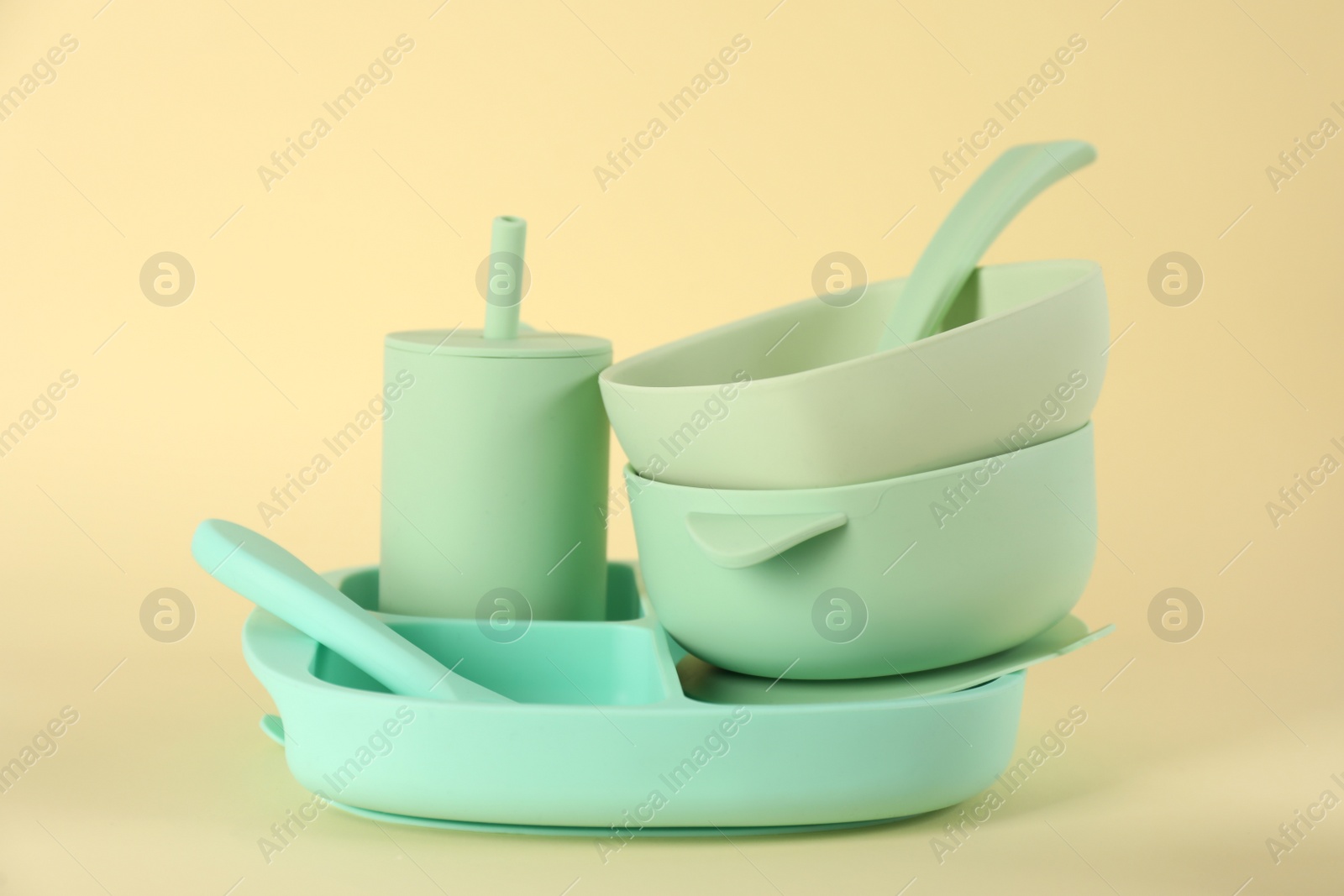 Photo of Set of plastic dishware on beige background. Serving baby food