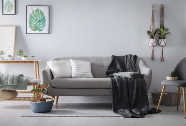 Soft knitted blanket on sofa in room. Home interior