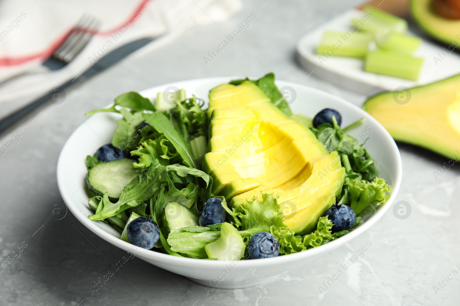 Photo of Delicious avocado salad with blueberries in bowl on grey marble table