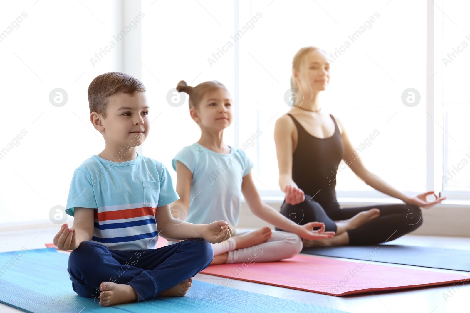 Photo of Little children and their teacher practicing yoga in gym