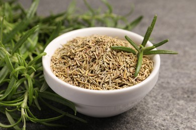 Dry and fresh rosemary in bowl on gray table, closeup