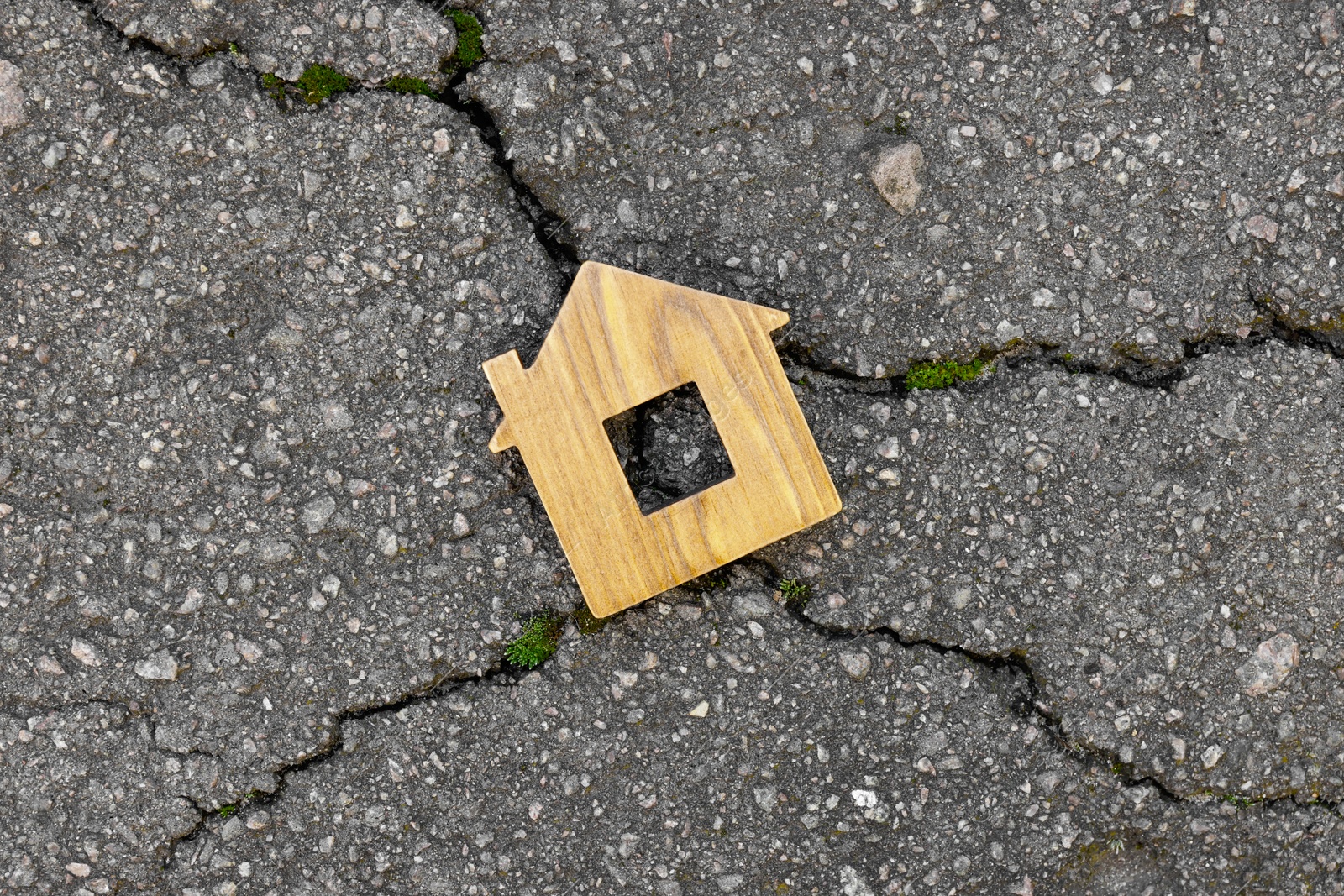 Photo of Wooden house model on cracked asphalt, top view. Earthquake disaster