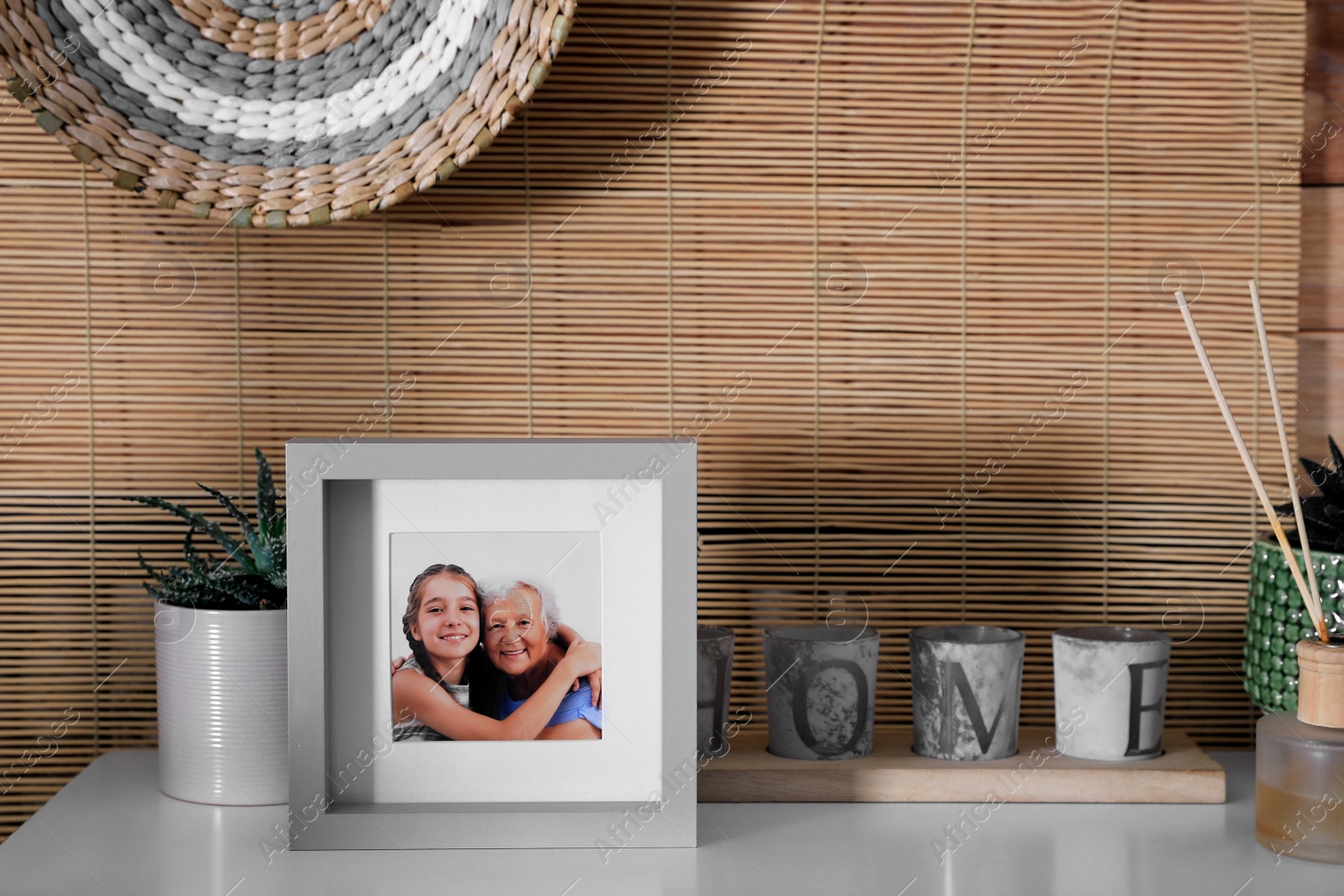 Photo of Frame with photo of elderly woman and her granddaughter on white table indoors