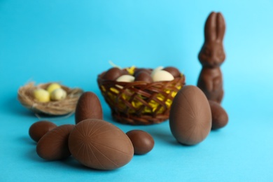 Sweet chocolate eggs and bunny on light blue background