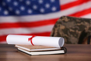 Photo of Diploma and notebooks on wooden table against flag of USA. Military education