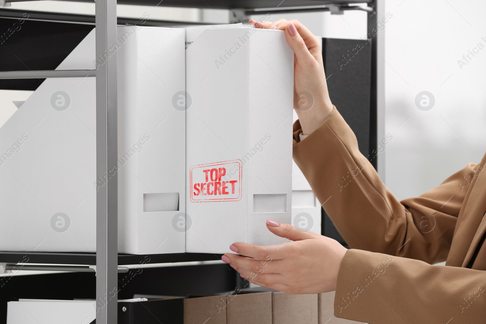 Image of Top Secret stamp. Woman taking folder with documents from shelf indoors, closeup