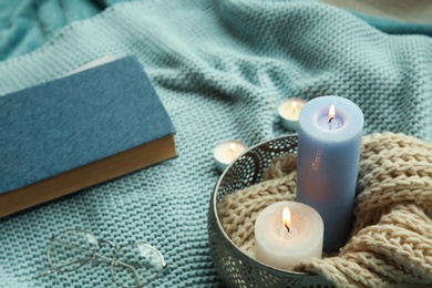 Photo of Beautiful composition with burning candles, eyeglasses and book on fabric