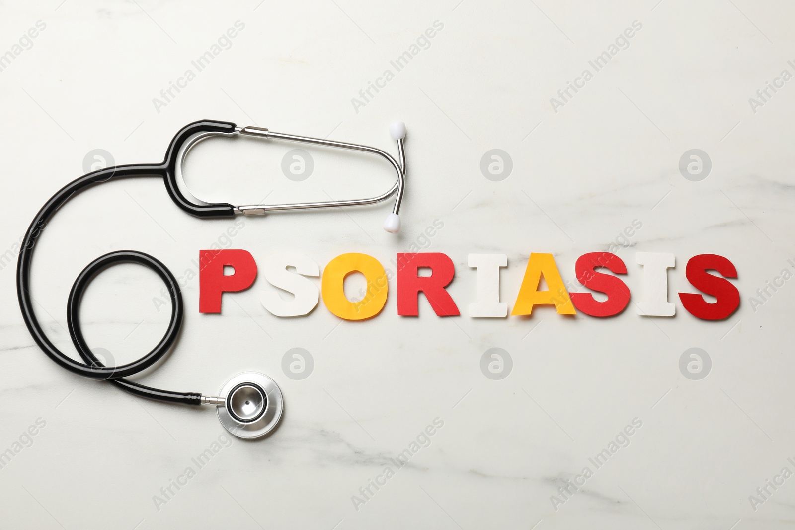 Photo of Word Psoriasis made of paper letters and stethoscope on white marble table, flat lay