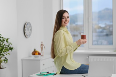 Photo of Beautiful young woman with delicious smoothie in office