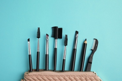 Photo of Set of professional eyebrow tools on turquoise background, flat lay