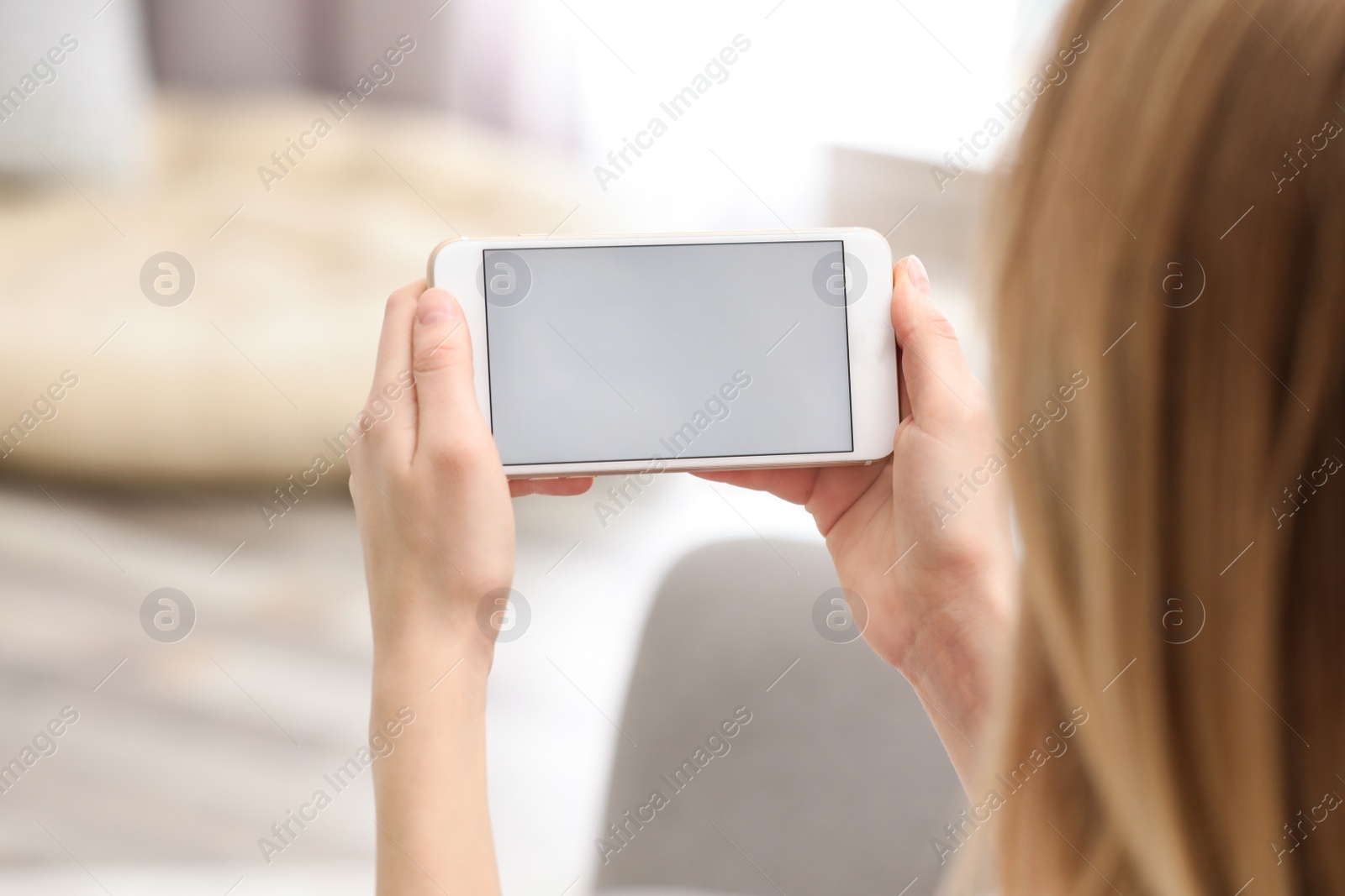 Photo of Young woman using video chat on smartphone at home, closeup. Space for design