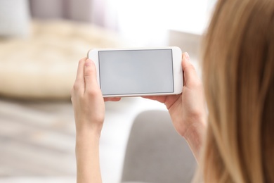 Young woman using video chat on smartphone at home, closeup. Space for design