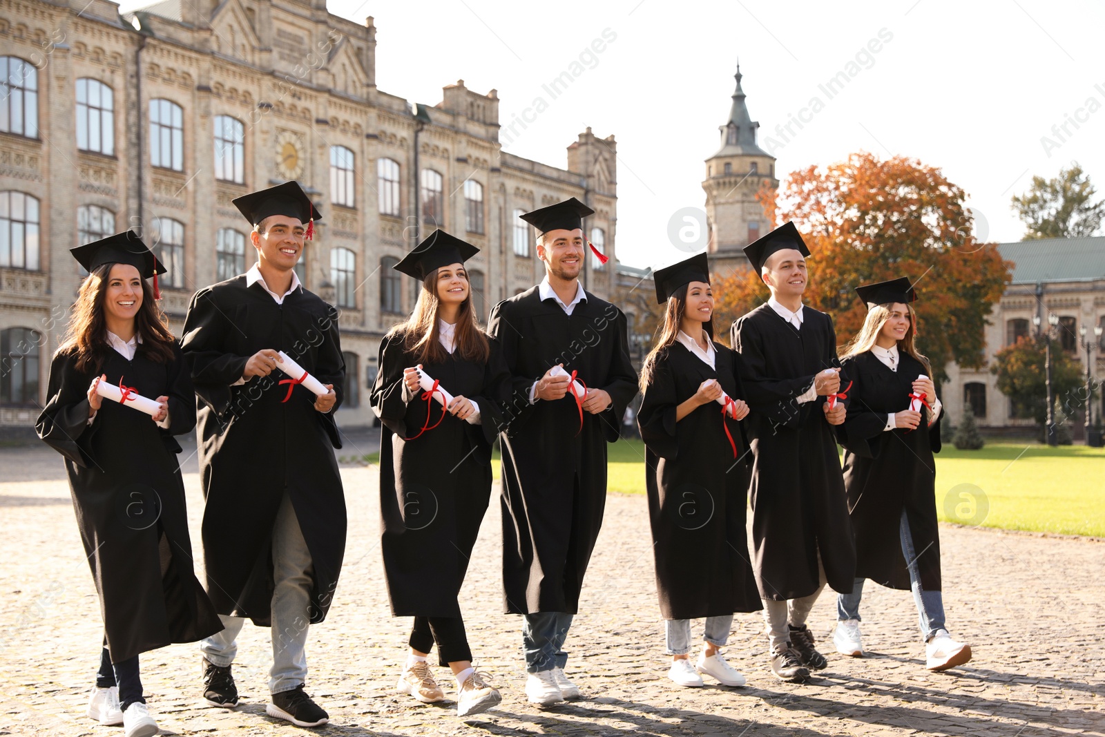 Photo of Happy students with diplomas outdoors. Graduation ceremony