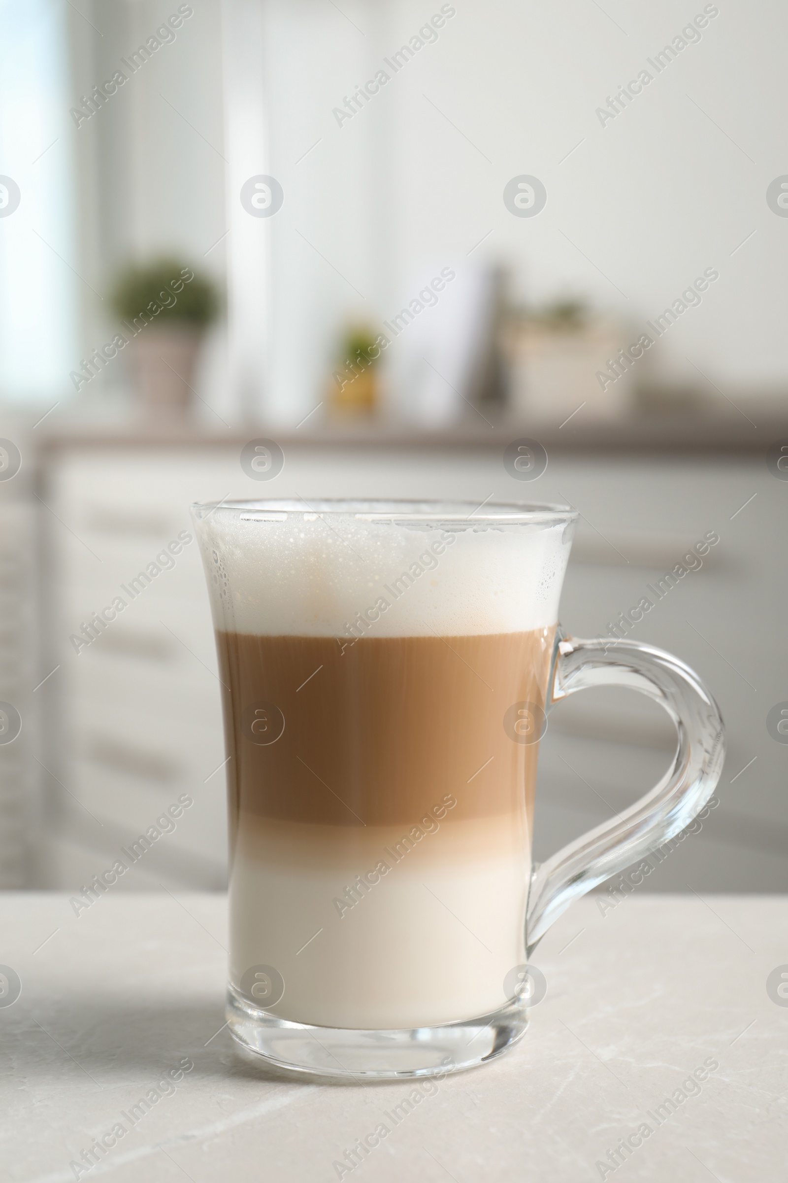 Photo of Glass cup of delicious layered coffee on light marble table indoors, space for text