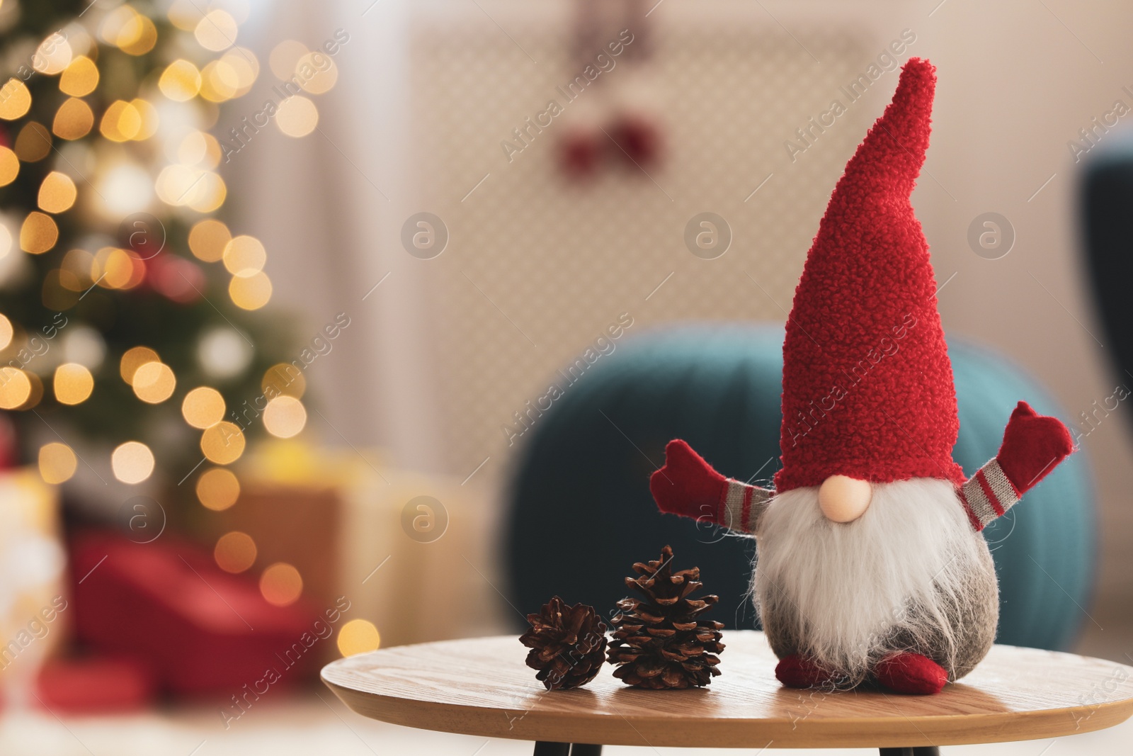 Photo of Cute Christmas gnome on wooden table in room, space for text