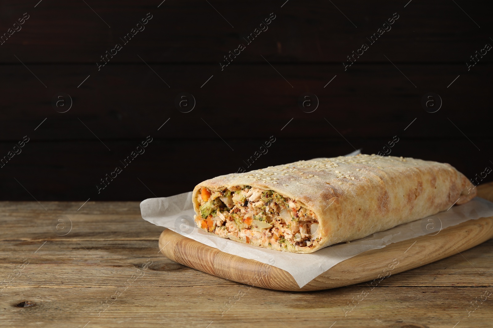 Photo of Tasty strudel with chicken and vegetables on wooden table. Space for text