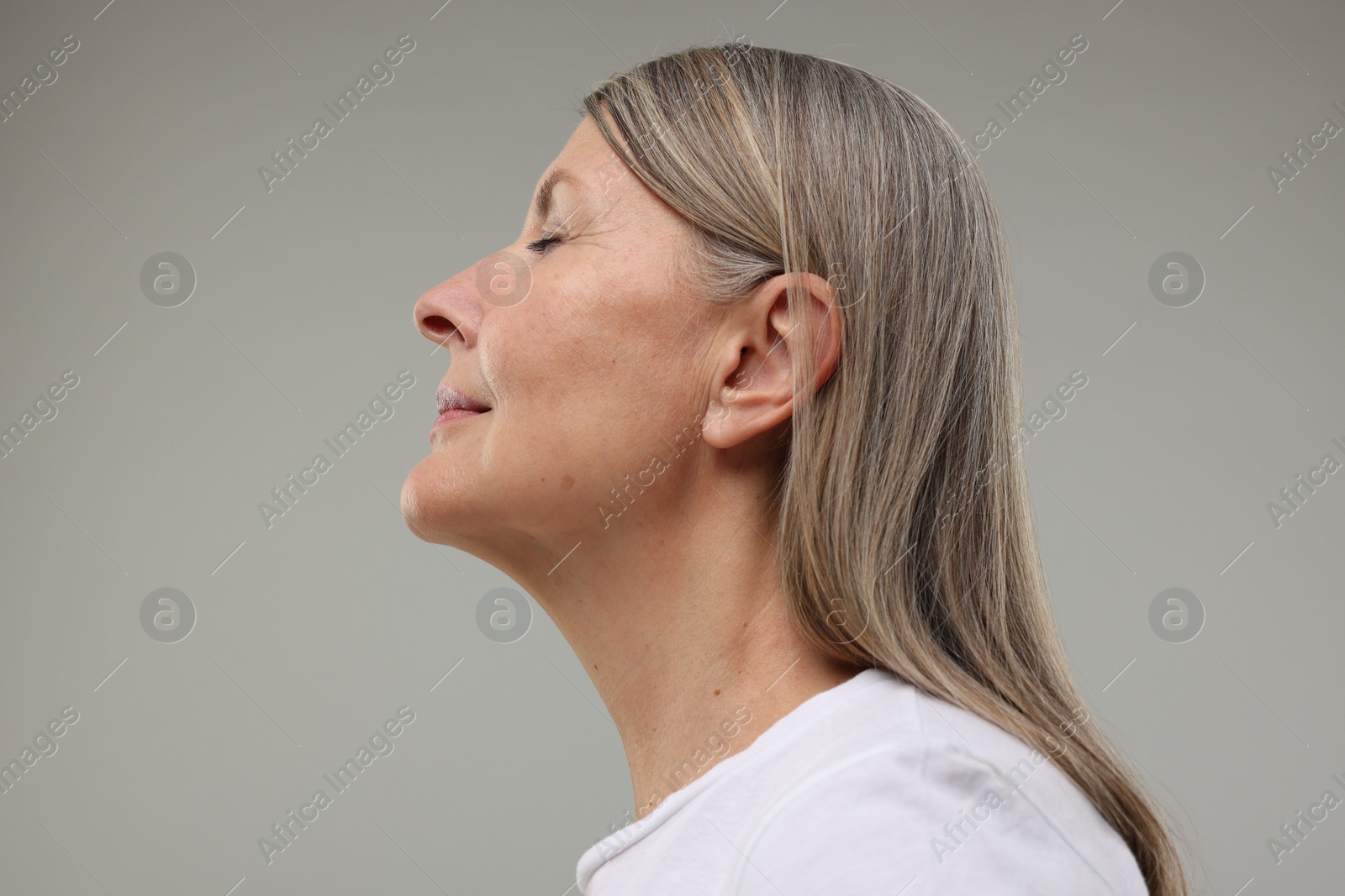 Photo of Beautiful woman with healthy skin on grey background, low angle view