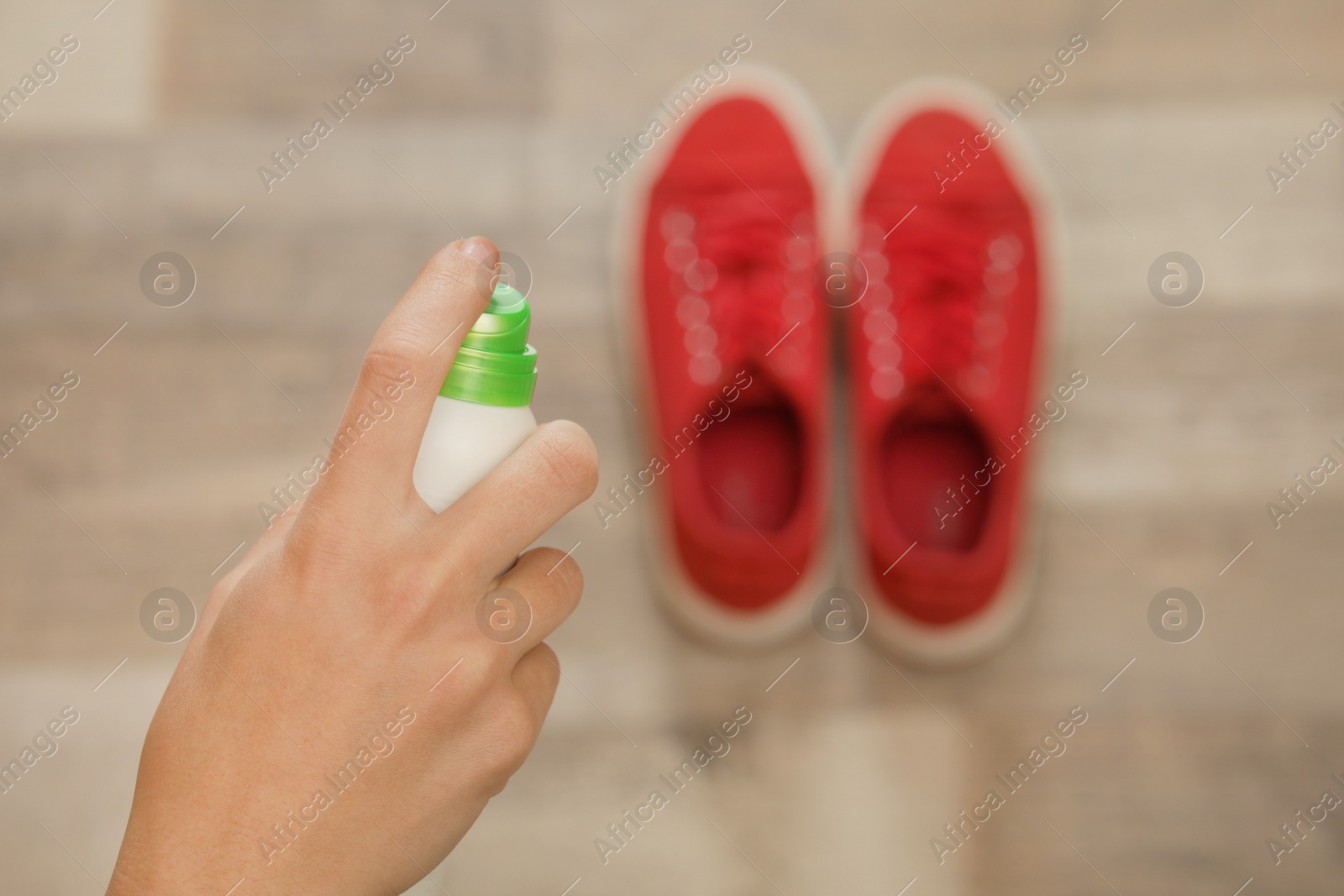 Photo of Woman spraying deodorant over pair of shoes at home, closeup. Space for text