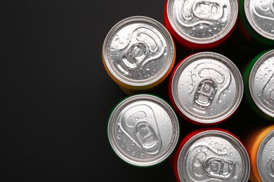 Photo of Energy drinks in wet cans on dark background, top view. Space for text