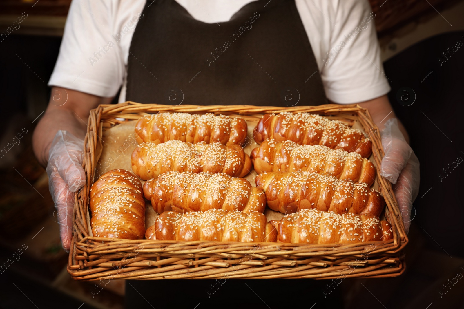 Photo of Baker with tray of fresh buns in store, closeup