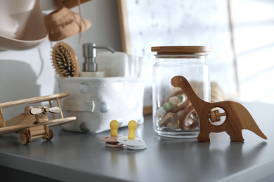 Pacifiers and wooden toys on grey table in child room