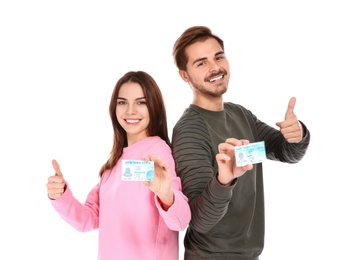 Happy young people with driving licenses on white background