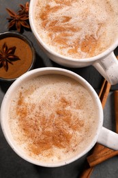 Photo of Cups of delicious eggnog with anise and cinnamon on grey table, flat lay