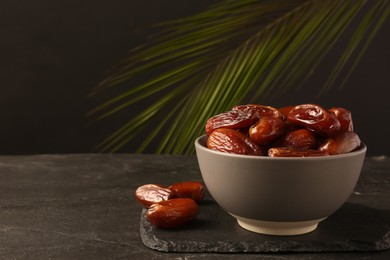 Photo of Tasty sweet dried dates on black table, space for text