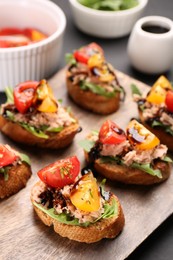 Photo of Delicious bruschettas with balsamic vinegar, tomatoes, arugula and tuna on grey table