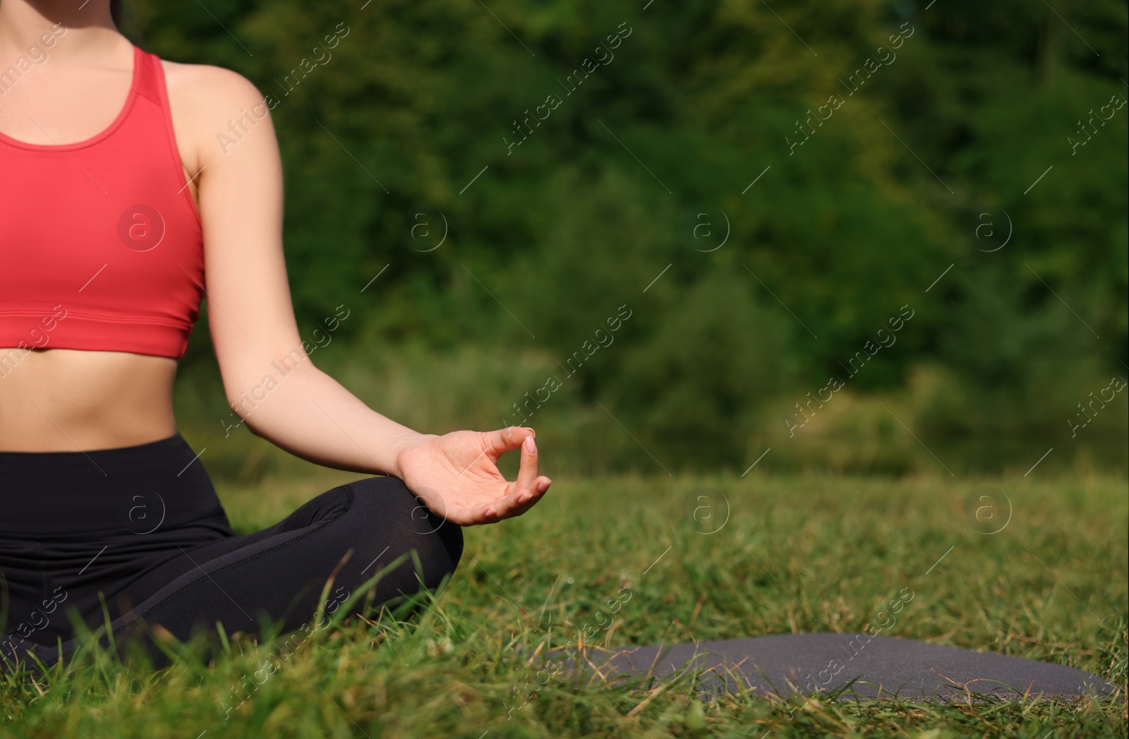 Photo of Woman practicing yoga on mat outdoors, closeup and space for text. Lotus pose