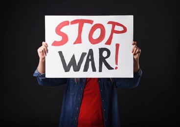 Photo of Woman holding poster with words Stop War on black background