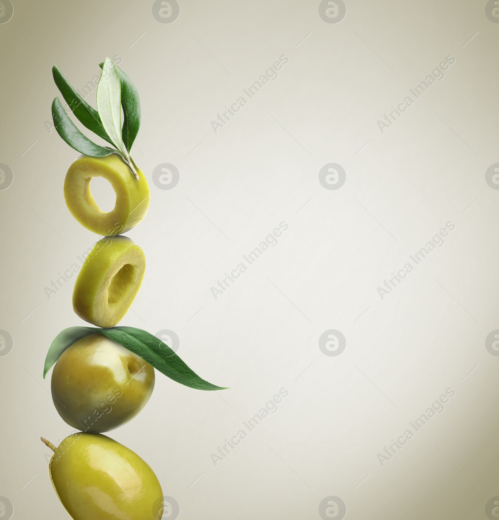 Image of Cut and whole green olives with leaves on dusty beige background, space for text